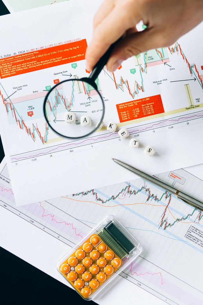 creative Magnifying glass focusing on market data and charts indicating financial analysis concept.
